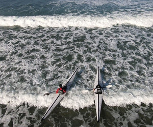 Two individuals paddling with their coast xt  in a body of water wit