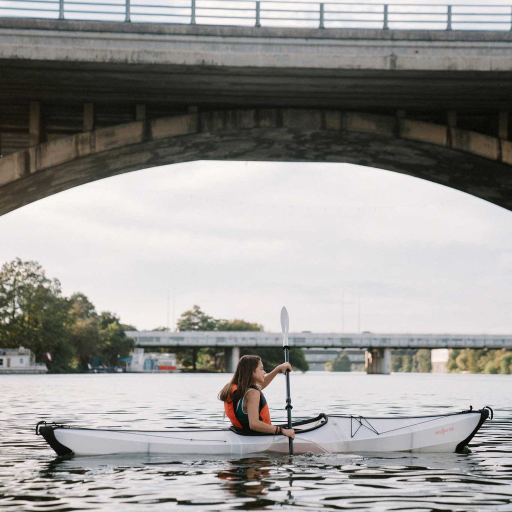 woman on the river paddling in her bay st kayak and using the oru paddles.