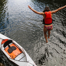 Beach LT kayak on a body of water and a woman jumping into the water (woman is wearing personal floatation device)