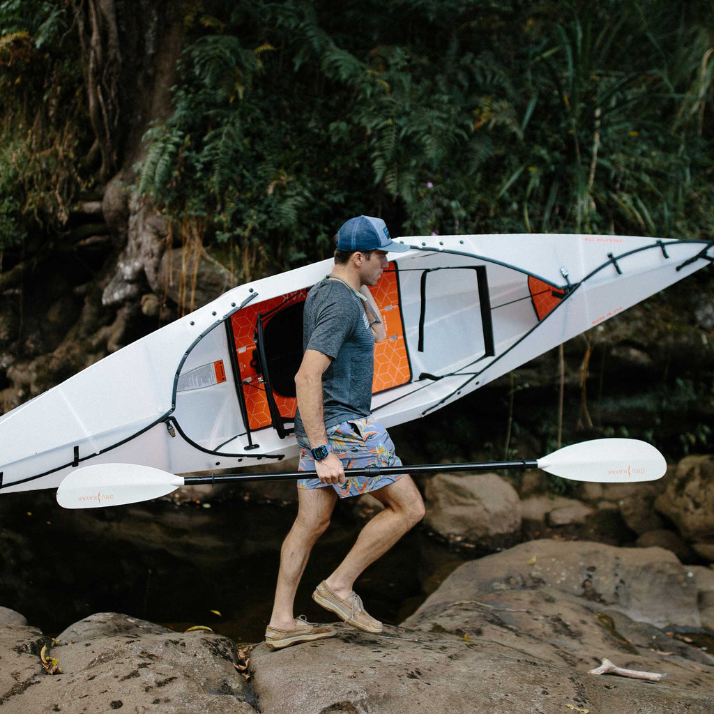 Man carrying beach lt kayak with oru paddle