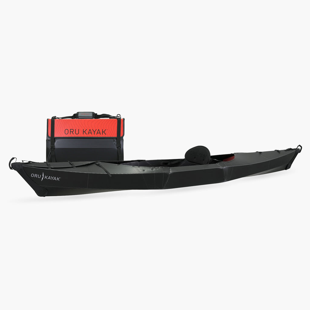 Side view of the Oru Kayak Beach model in black, shown fully assembled in front of its compact folded box form.