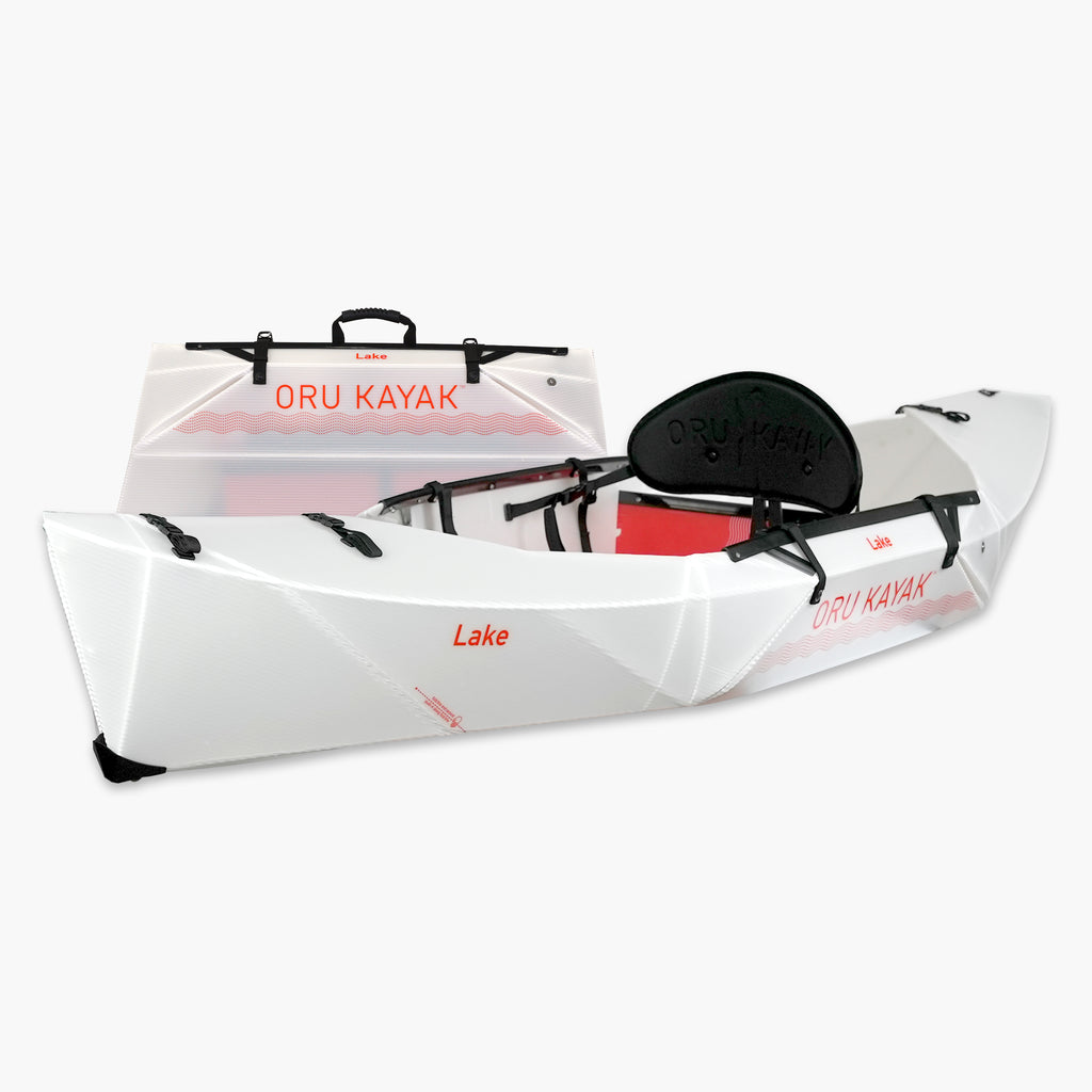 Side view of the Oru Kayak Lake Sport model in white, shown fully assembled in front of its compact folded box form.