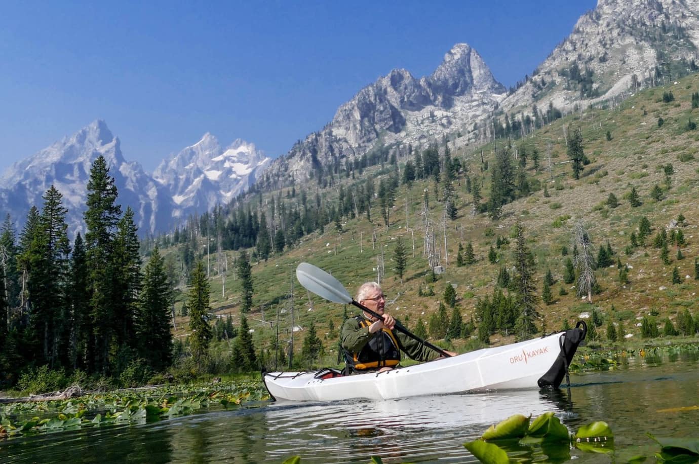 Man kayaking on the lake surrounded by mountains