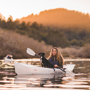Woman with dog paddling on a lake kayak