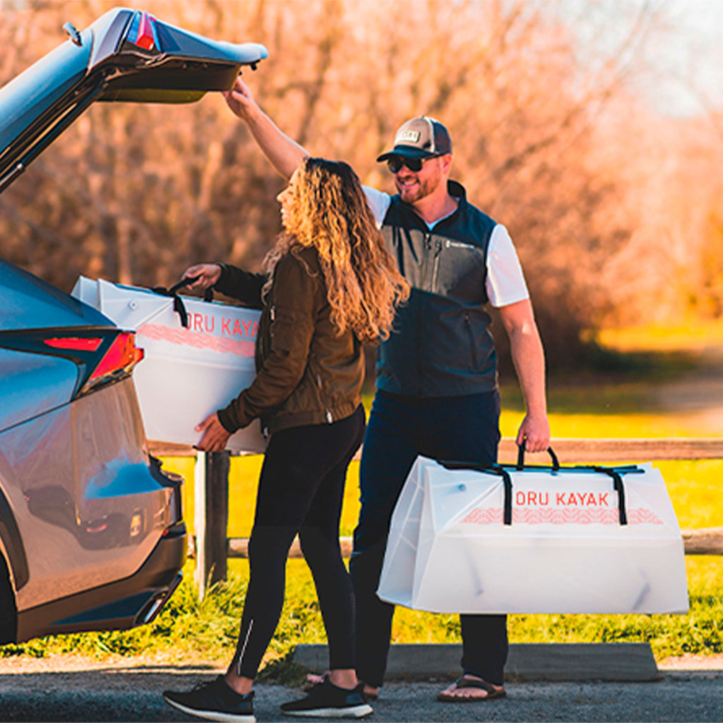 2 people loading their lake kayak (folded) in their trunk