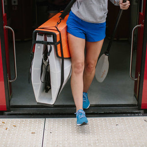 Person getting off the train with their bay st kayak model folded and oru paddle 