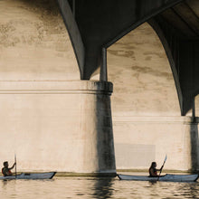 2 people paddling underneath the bridge on their bay st kayaks. 